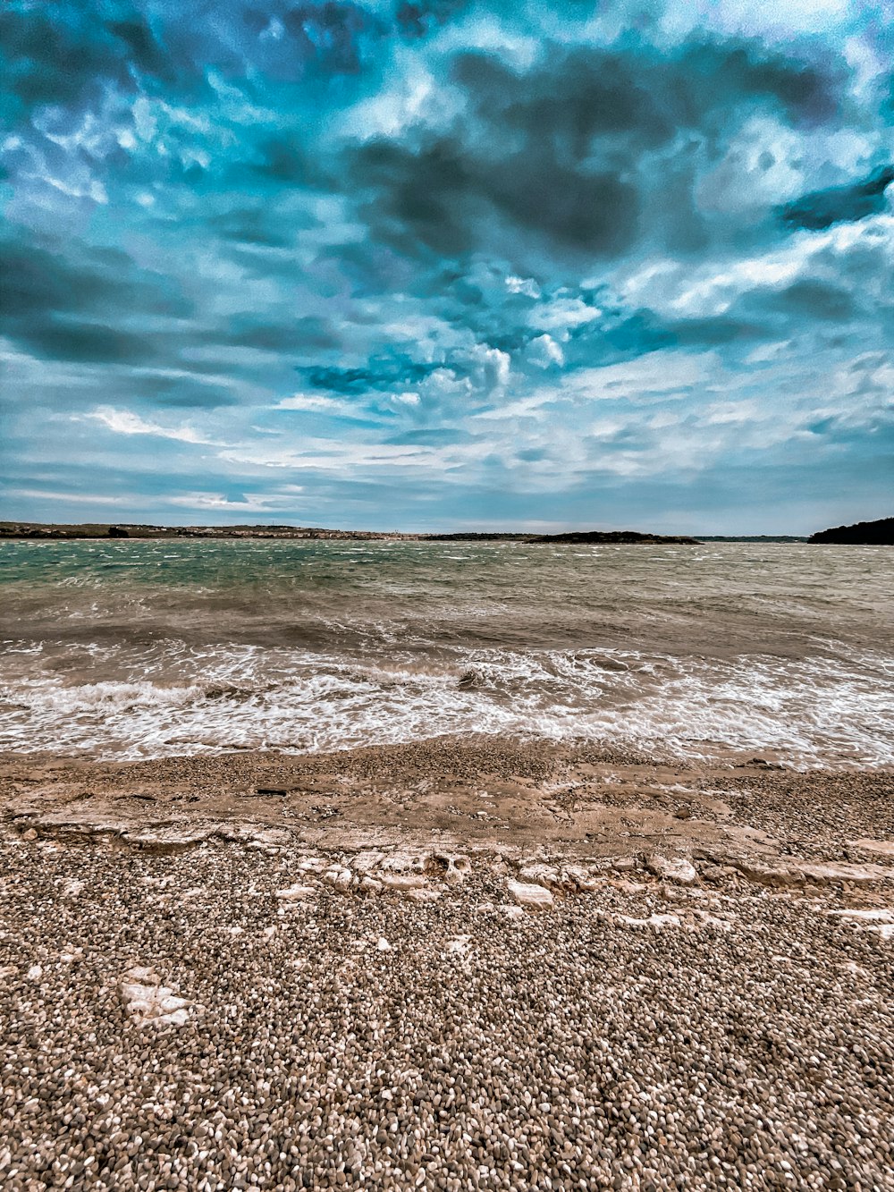 brown sand near body of water under blue sky during daytime