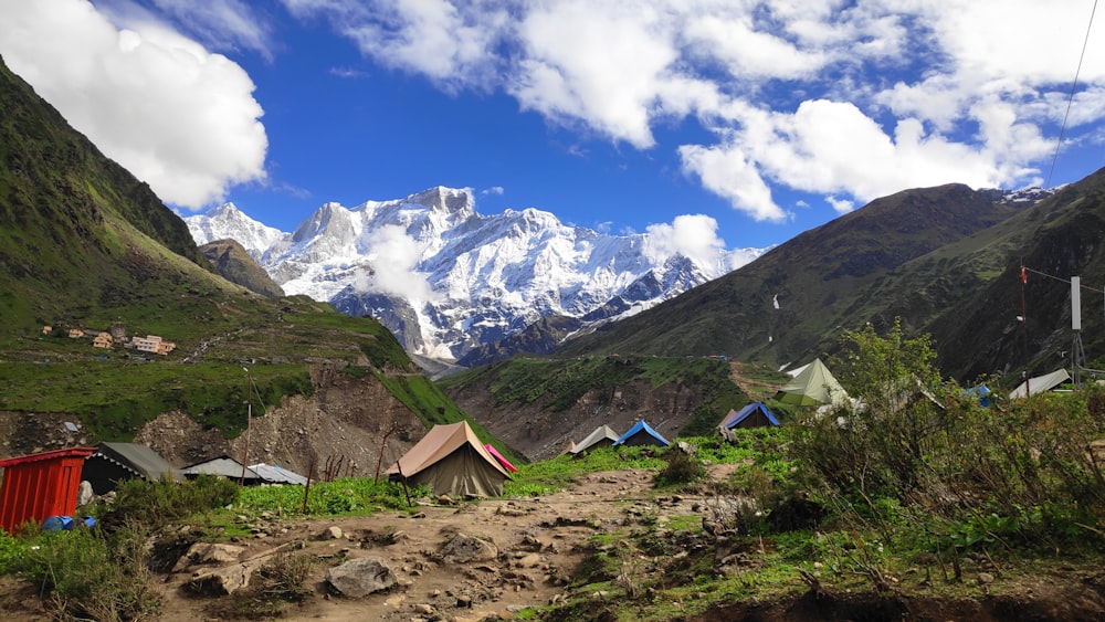 blue tent on brown field near mountain under blue sky and white clouds during daytime