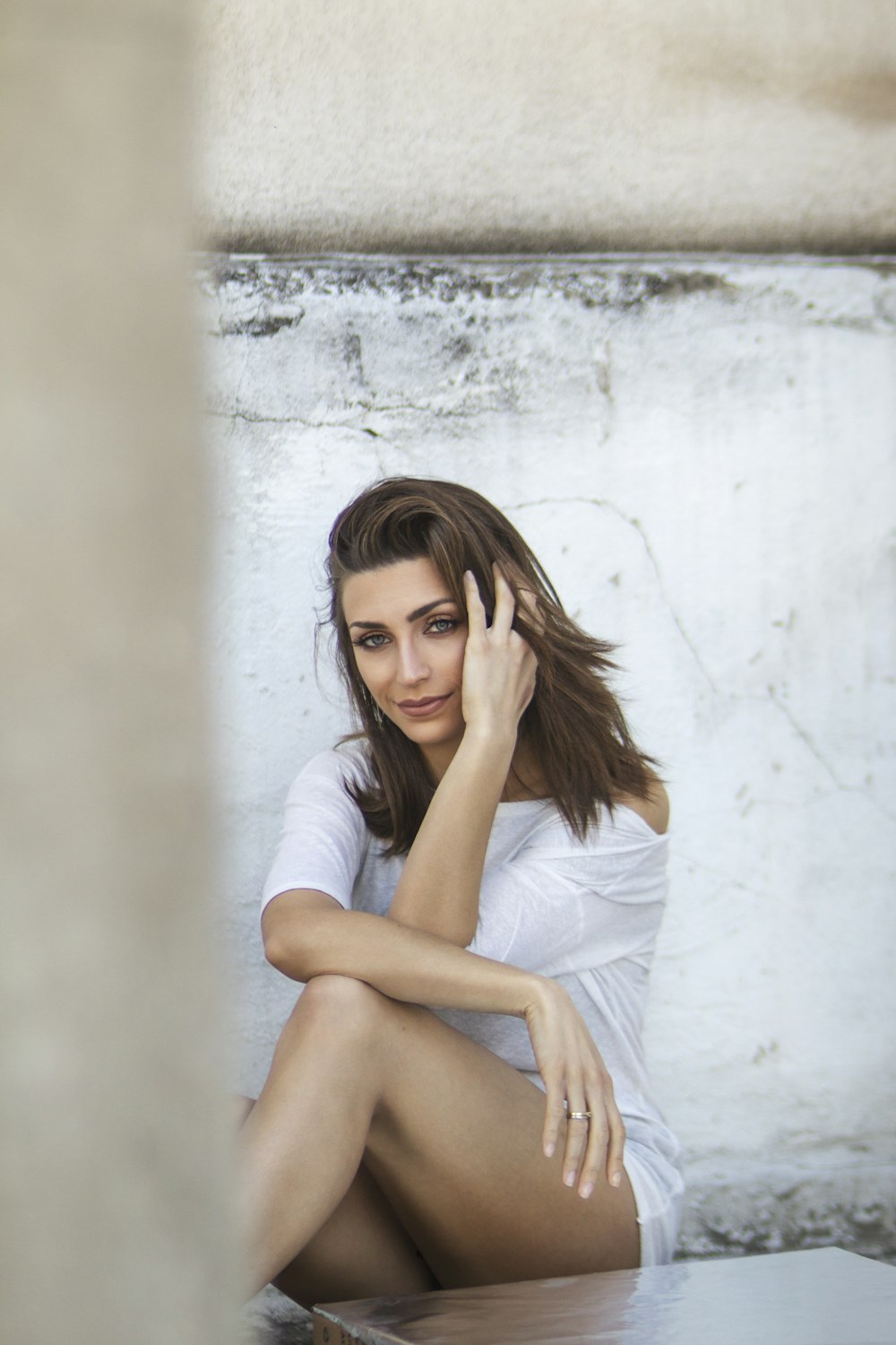 woman in white dress leaning on wall