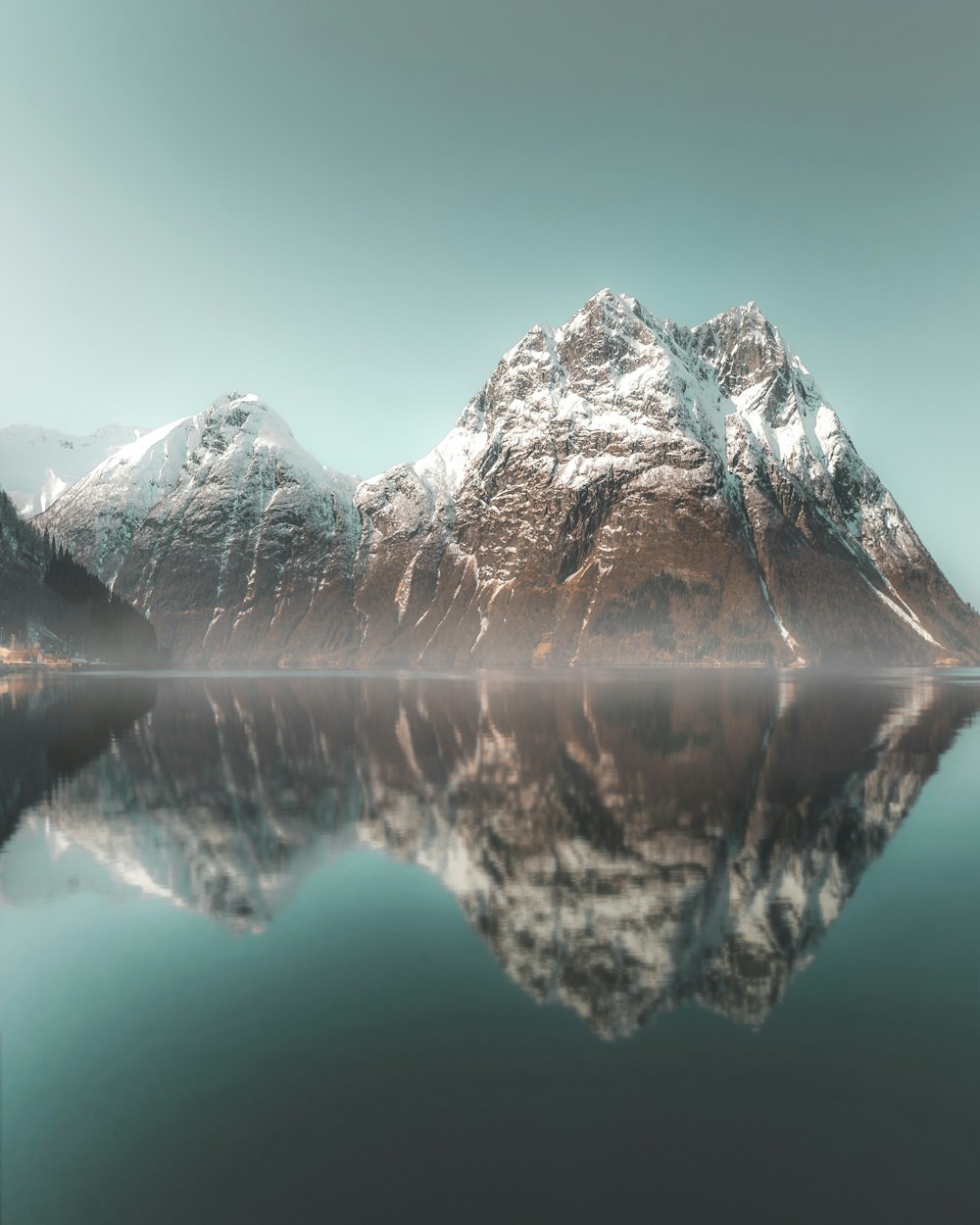 a mountain range is reflected in the still water of a lake