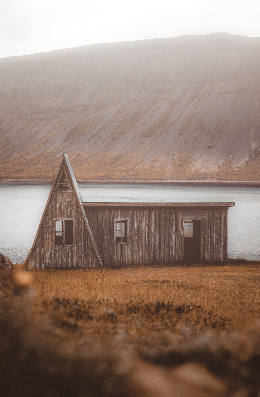 brown wooden house near body of water during daytime