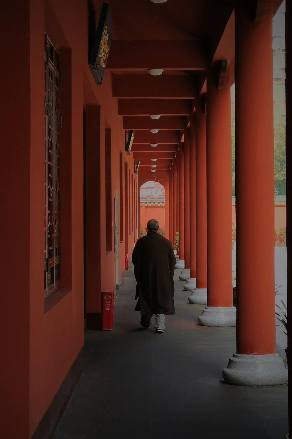 man in black coat walking on hallway