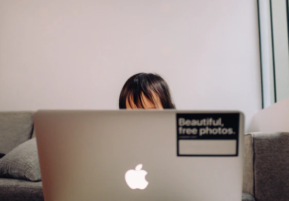 A thoughtful young person browsing a laptop in a cozy room, symbolizing digital awareness and safety.