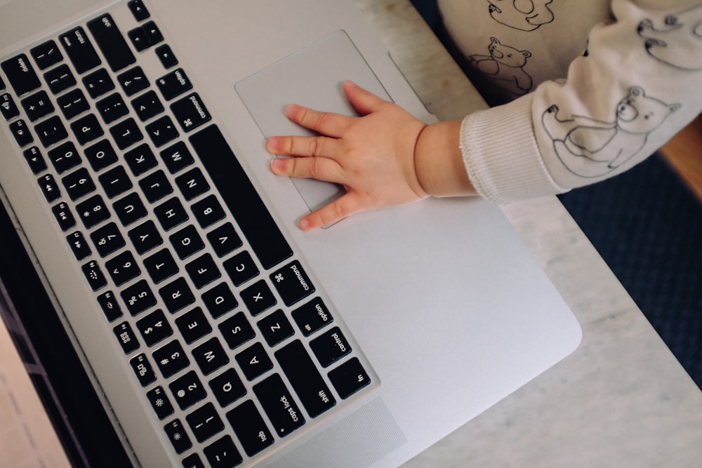 person using macbook pro on white table