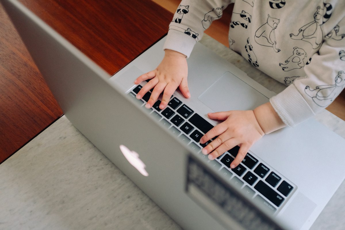 A young child's hands resting on a laptop keyboard