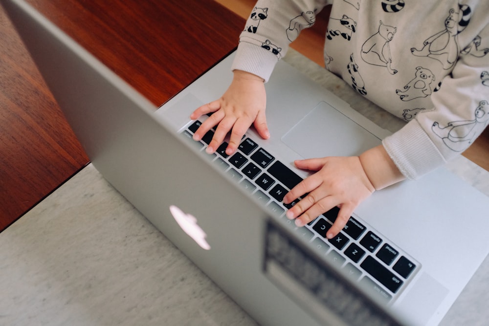 a young child is typing on a laptop