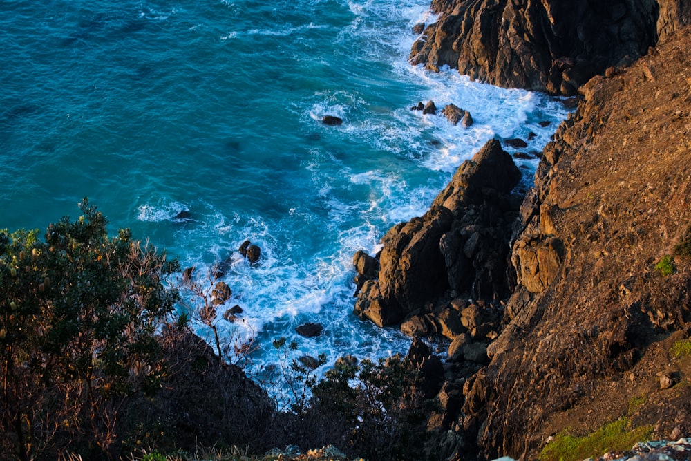 brown rocky mountain beside blue sea during daytime