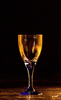 A close-up of a golden wine glass catching the light against a deep burgundy backdrop.