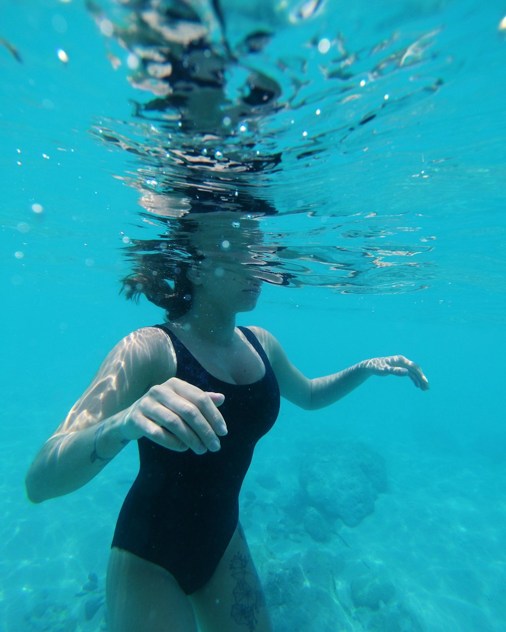 mujer en traje de baño negro bajo el agua