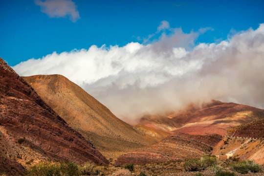 brown mountain under white clouds and blue sky during daytime in Jujuy Argentina