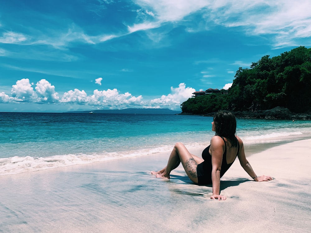 woman in black bikini lying on beach during daytime