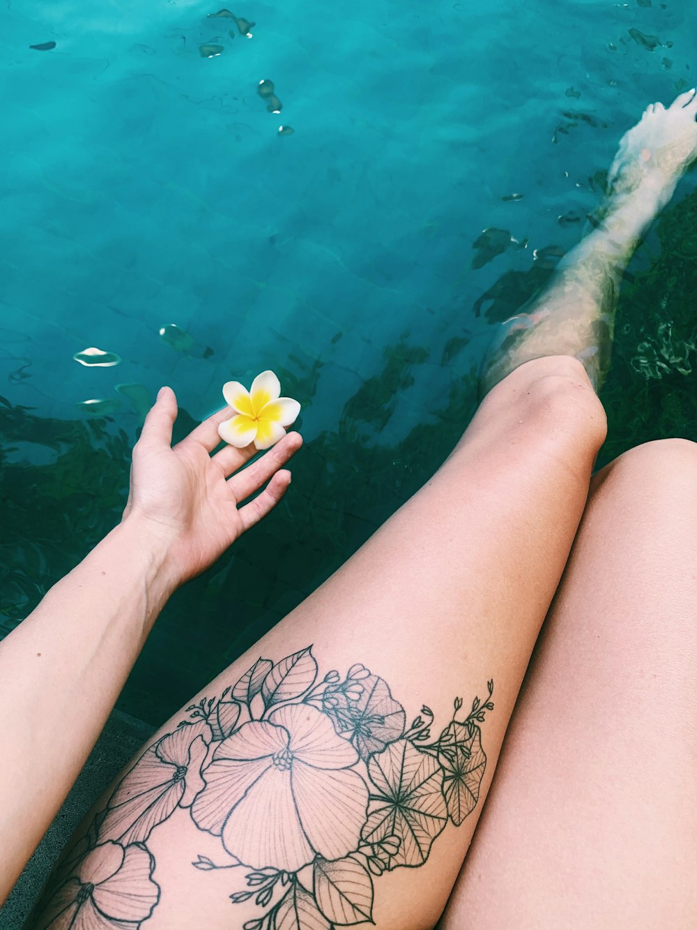 pessoa com tatuagem floral preta e vermelha na perna