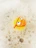 A rubber duck wearing red goggles is partially submerged in soapy water, surrounded by thick layers of foam and bubbles.