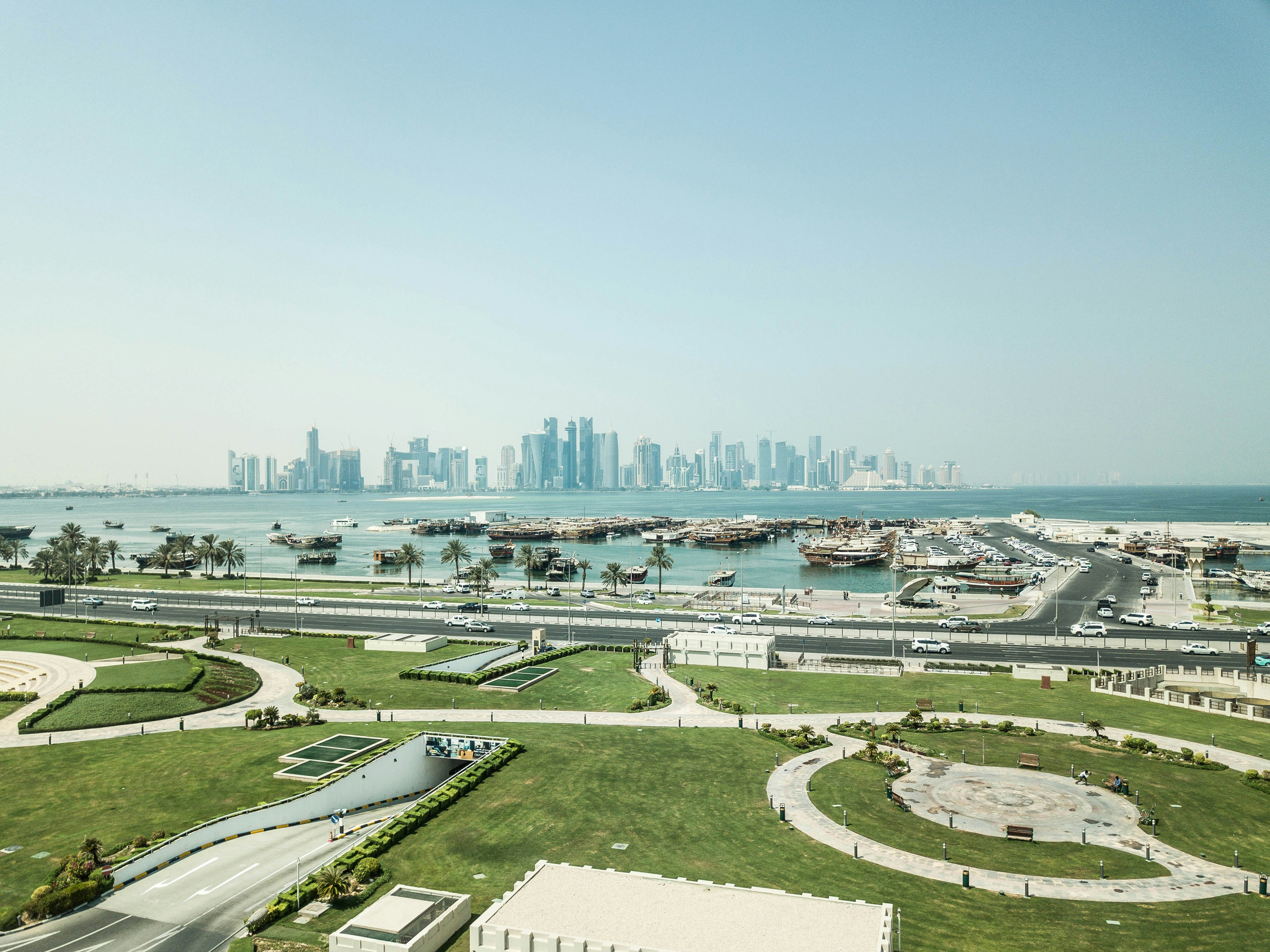 green grass field near body of water during daytime, Skyline of Doha. Доха, Катар, город на заливе.