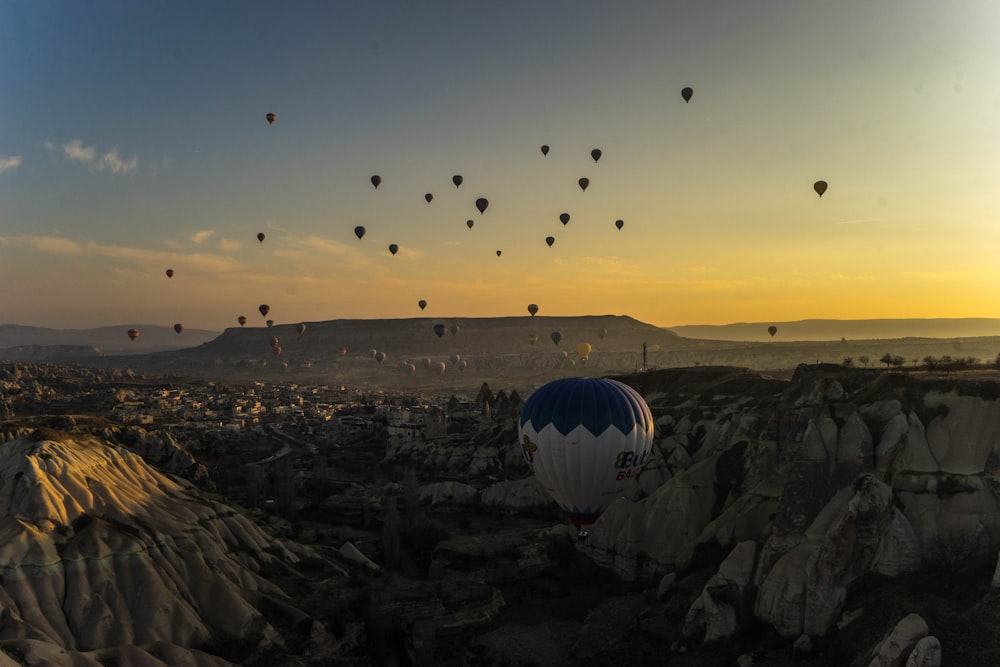 hot air balloons flying over the city during sunset