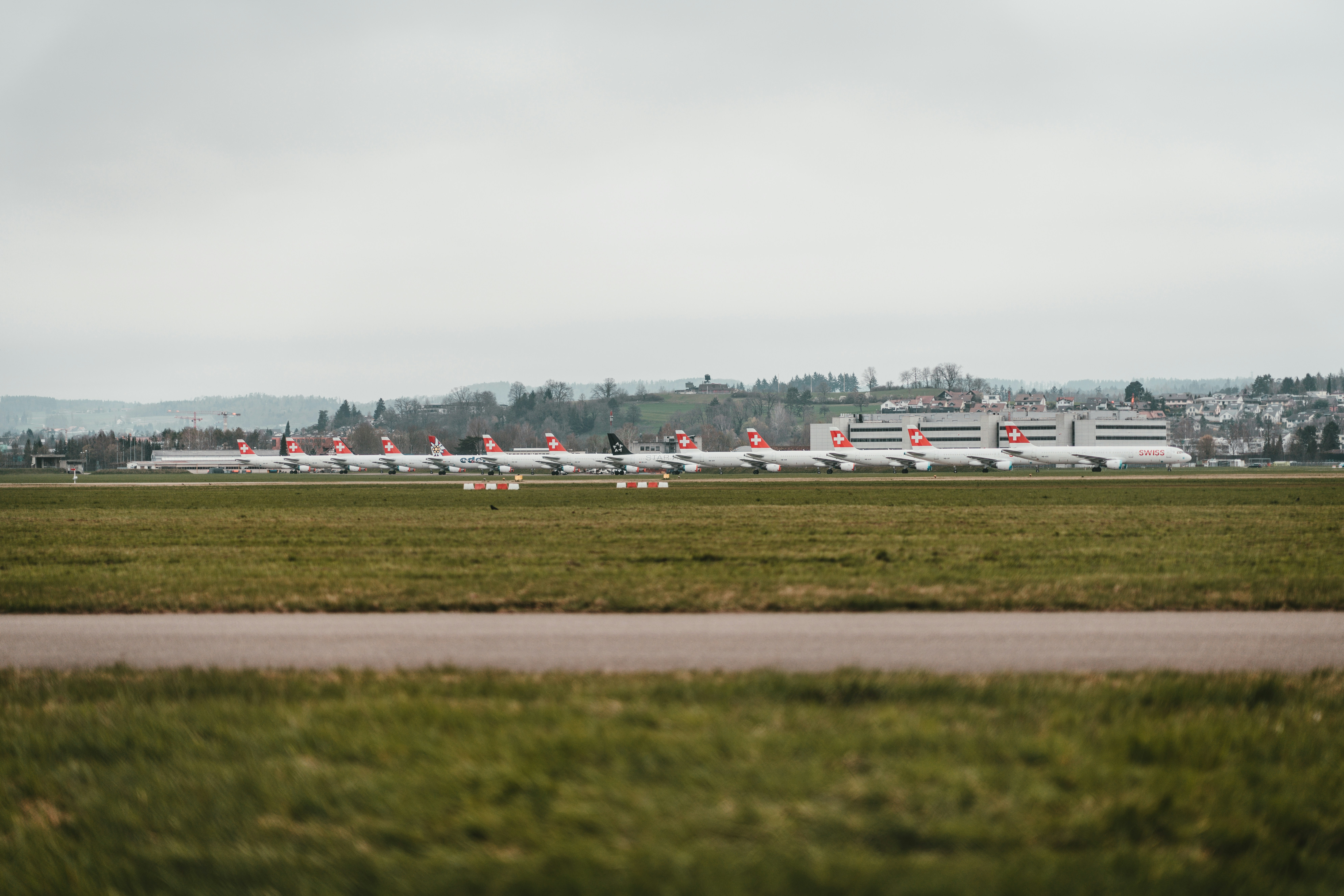 white and red plane on green grass field under white clouds during daytime