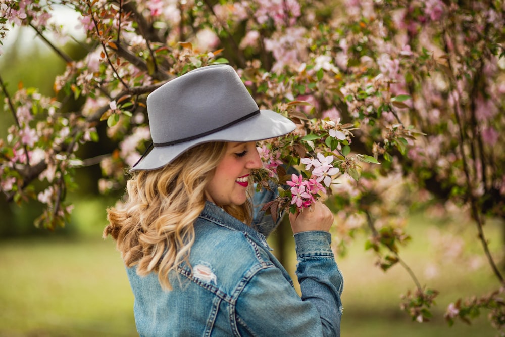 woman in blue denim jacket and blue denim jeans holding pink flowers