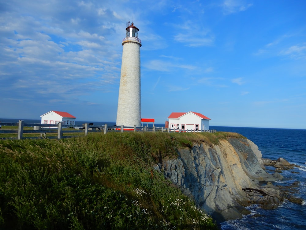 white and brown lighthouse on brown rock formation under blue sky during daytime