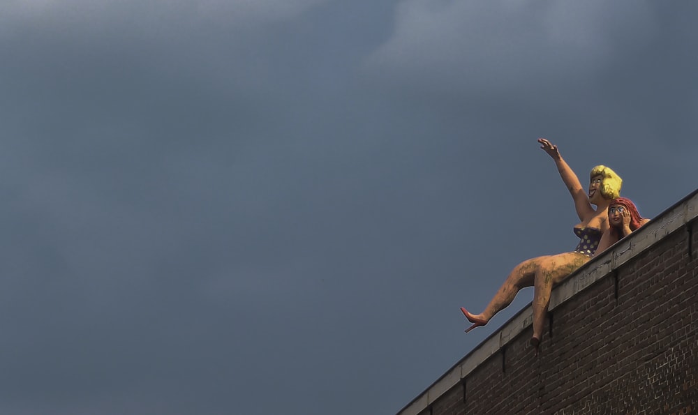 man in orange shorts jumping on brown brick wall under blue sky during daytime