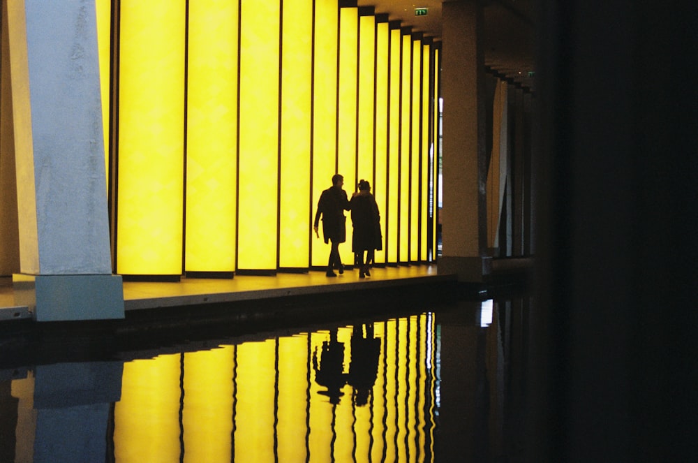 silhouette of 2 person walking on hallway
