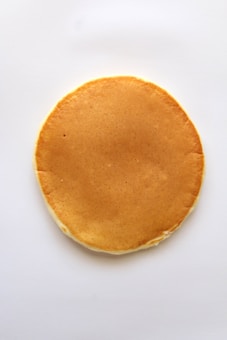 A single, round pancake with a golden-brown color placed on a plain white background.