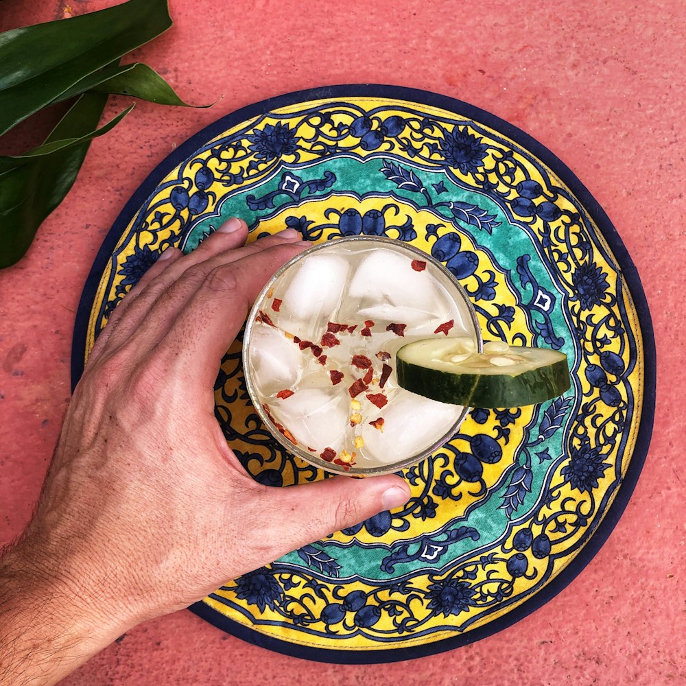 person holding blue and white ceramic bowl with ice cream