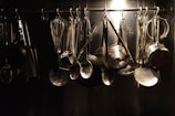 Various cooking utensils like spatulas, whisks, and ladles hanging from a rustic kitchen rack.