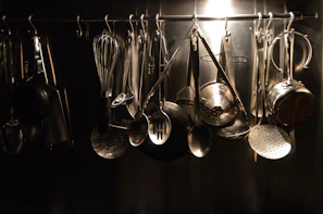 Elegant stainless steel kitchen accessories like ladles and strainers hanging from a rack.