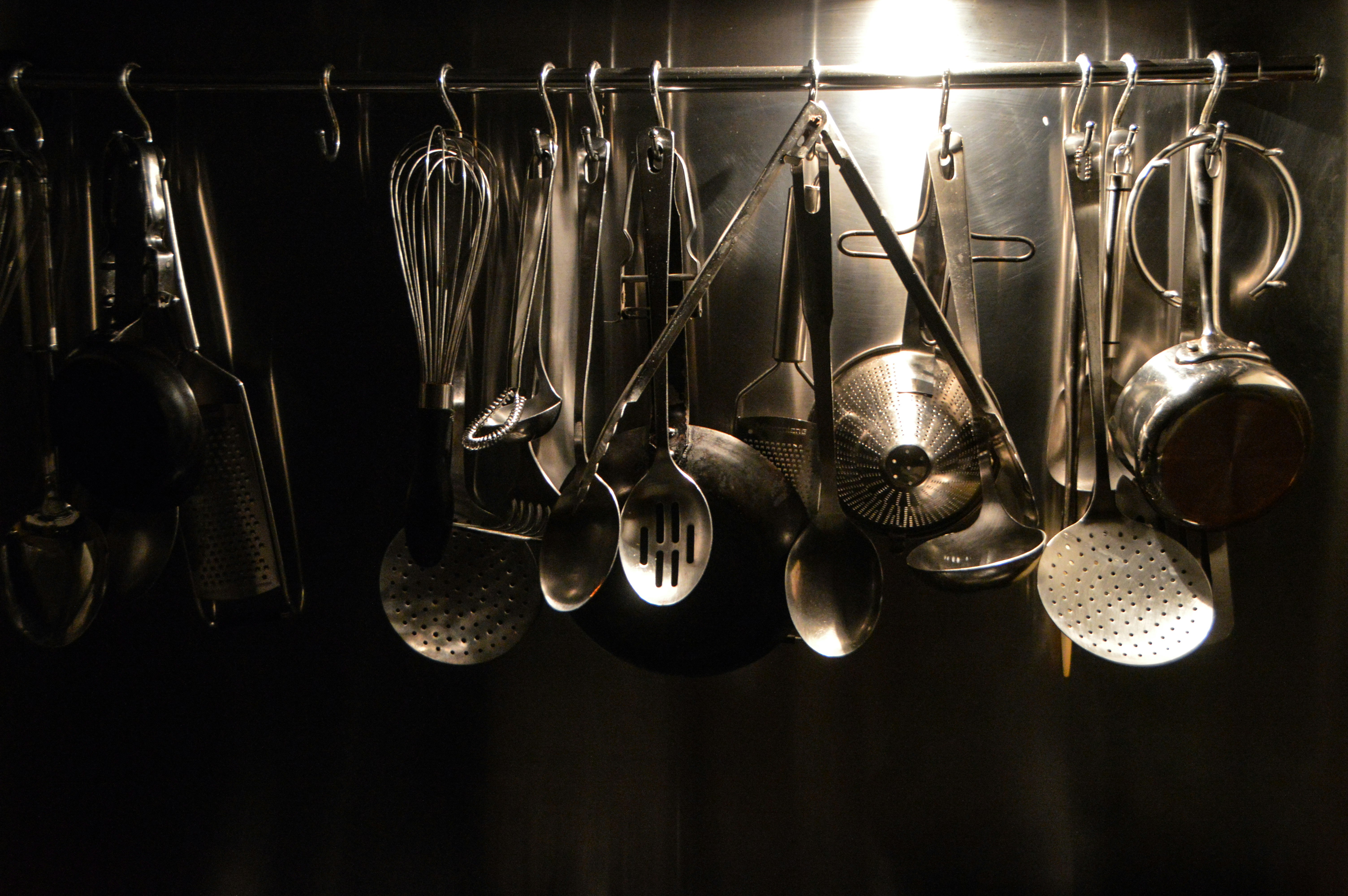 Metal kitchen utensils hinging on a rail. Top lighting and shining edges caught my eye