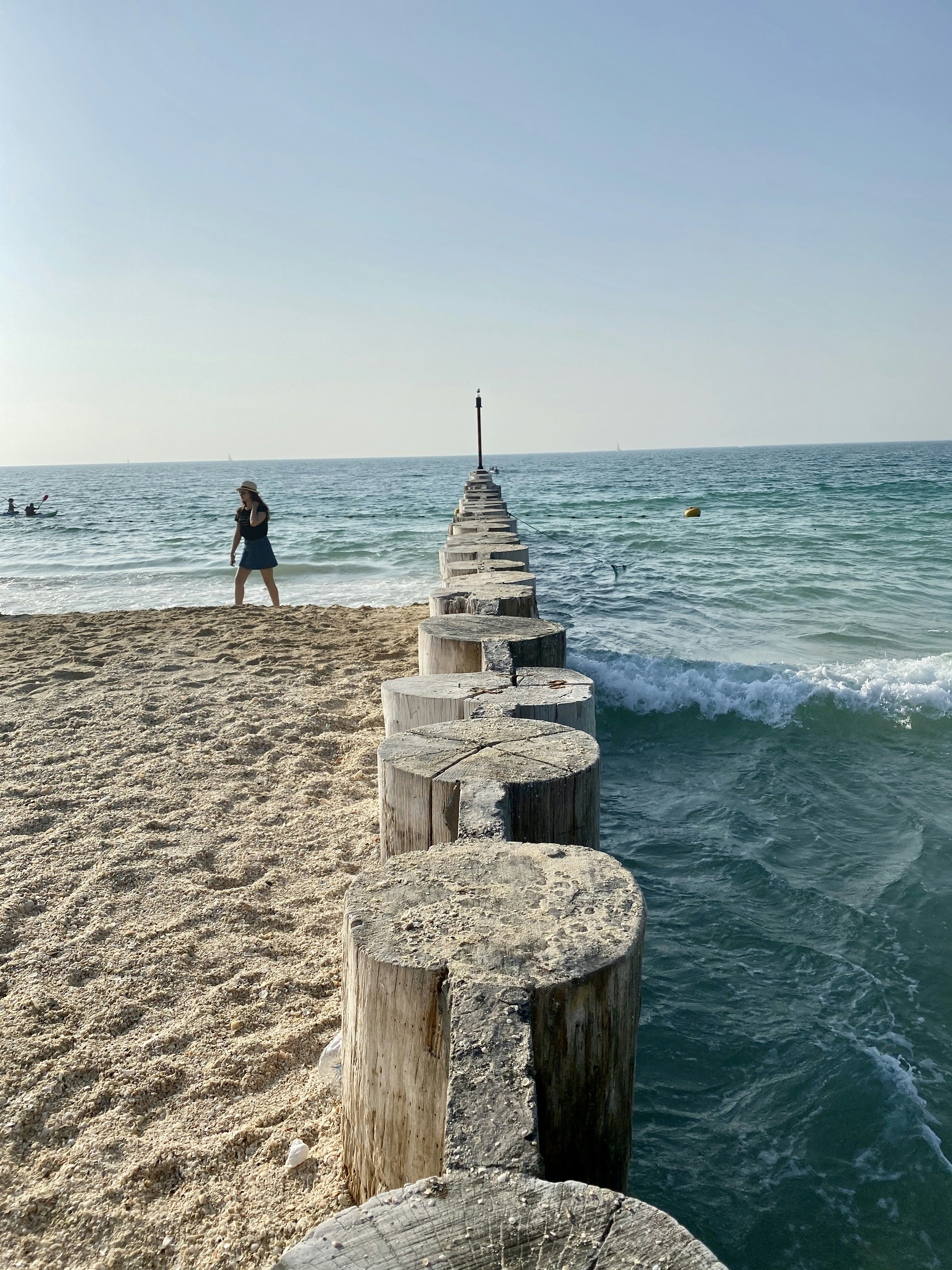 femme en débardeur noir et short noir debout sur le quai en bois brun pendant la journée