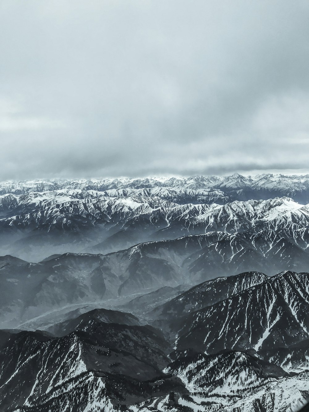 snow covered mountains under cloudy sky during daytime