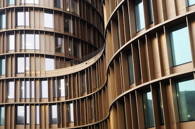 Curved architectural structure with vertical slats separating reflective glass windows. The building's facade creates an undulating pattern with a sleek and modern design.