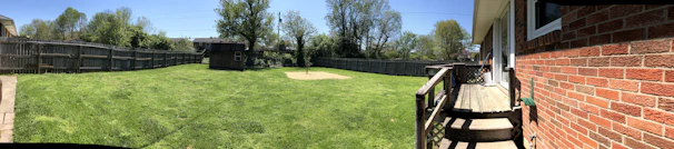 A freshly built wooden fence surrounding a suburban backyard, with a 4tress worker finishing the final touches.