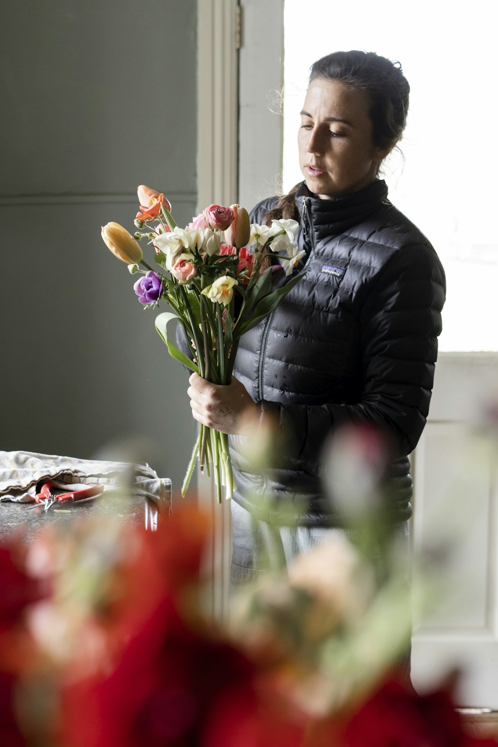 donna in camicia nera a maniche lunghe che tiene bouquet di fiori rossi e bianchi