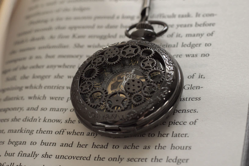 Close-up of a finely detailed antique pocket watch resting on an aged leather-bound book.