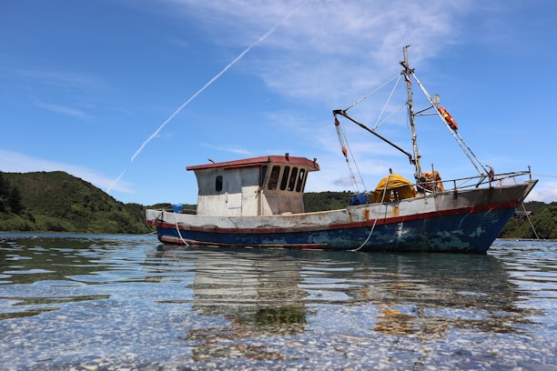 A sleek fishing boat anchored near a calm lake at sunrise, ready for a day of fishing.