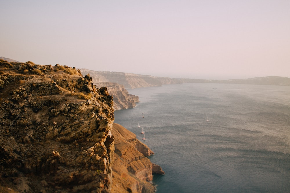 a body of water sitting next to a rocky cliff