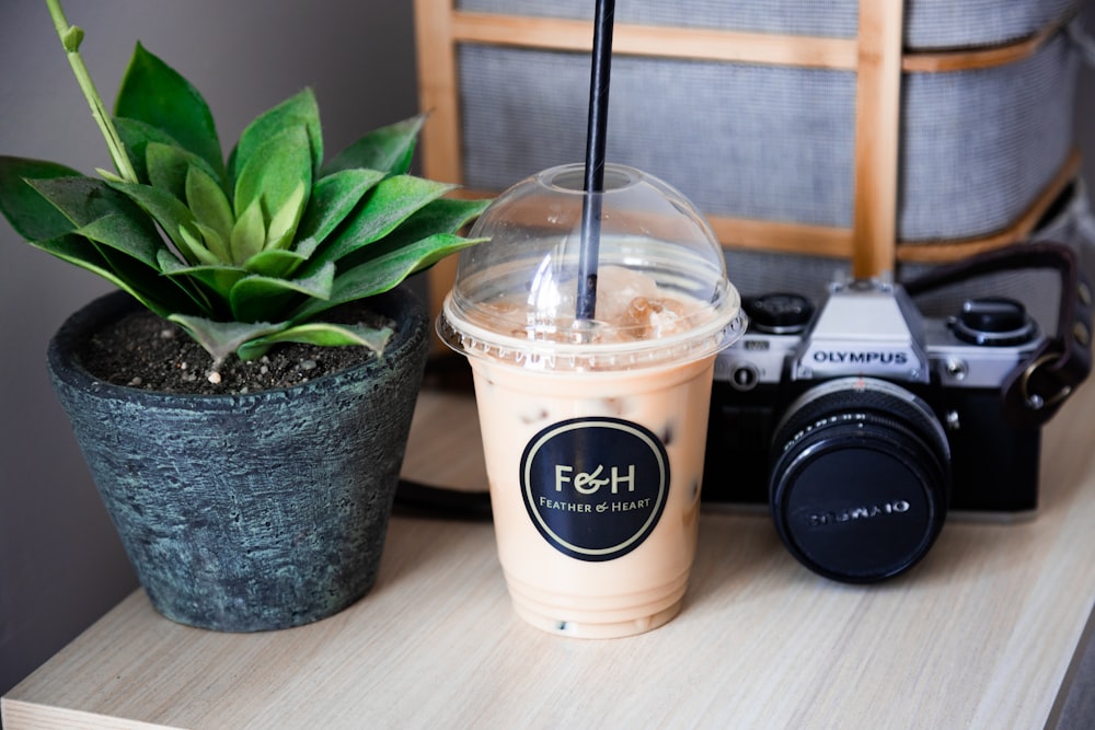 white and black disposable cup with black and silver nikon dslr camera