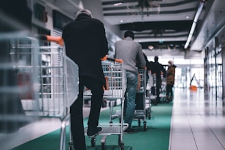 man in black long sleeve shirt and black pants standing on shopping cart