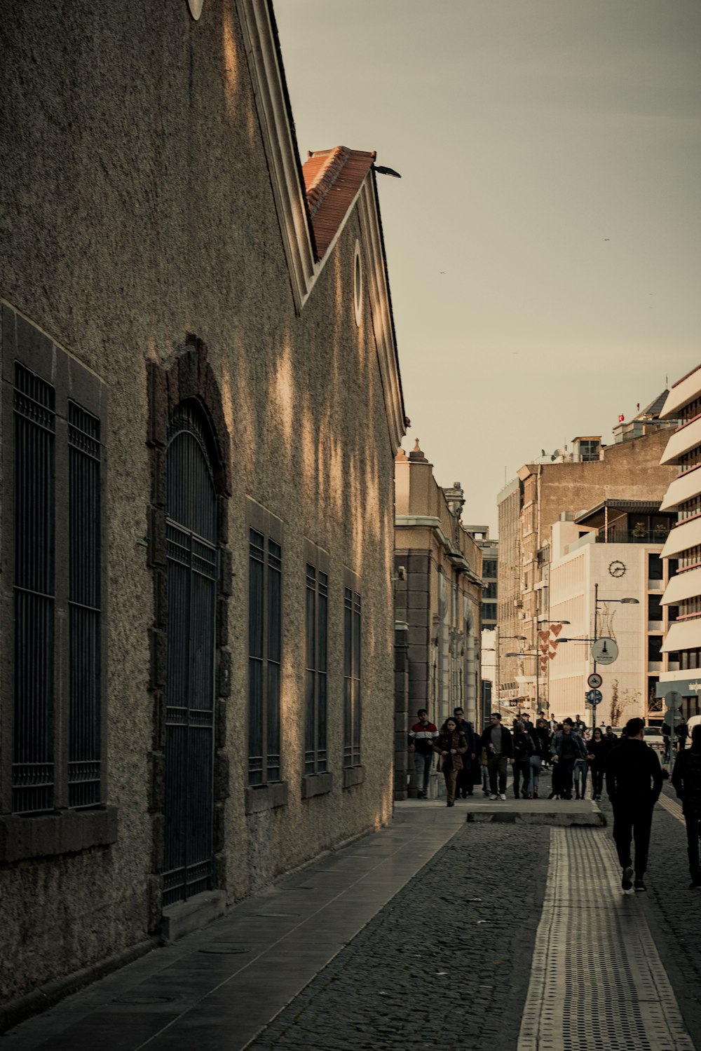 people walking on sidewalk near brown concrete building during daytime