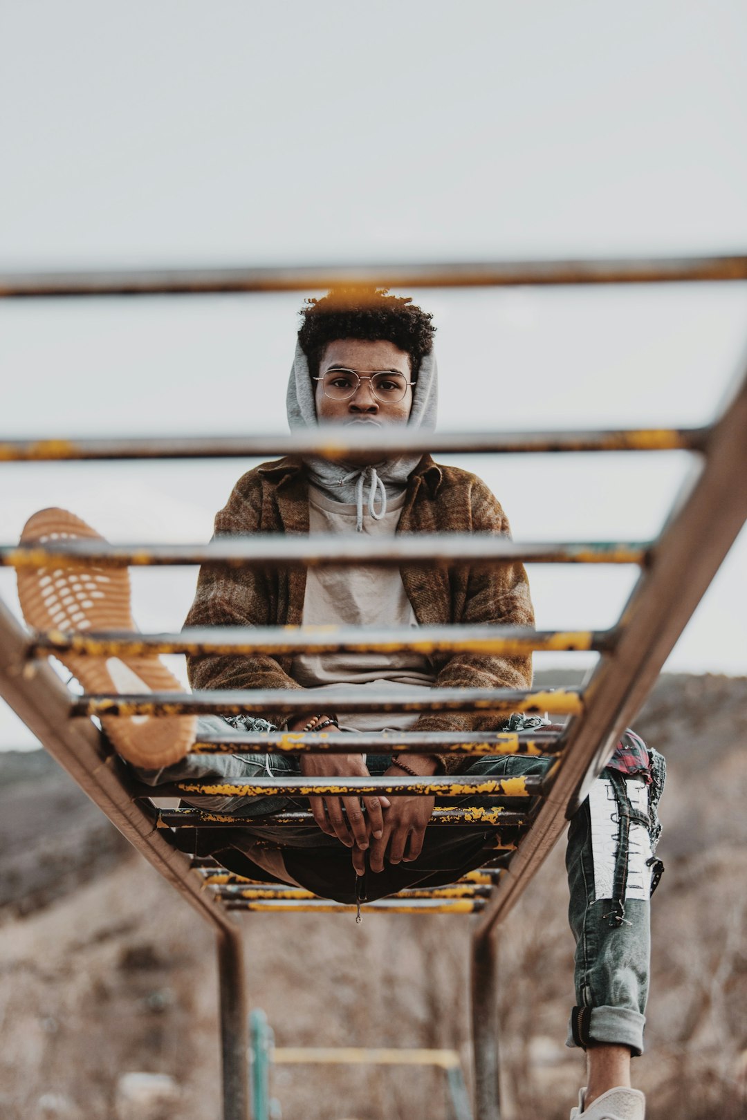 man in brown jacket sitting on brown wooden ladder during daytime