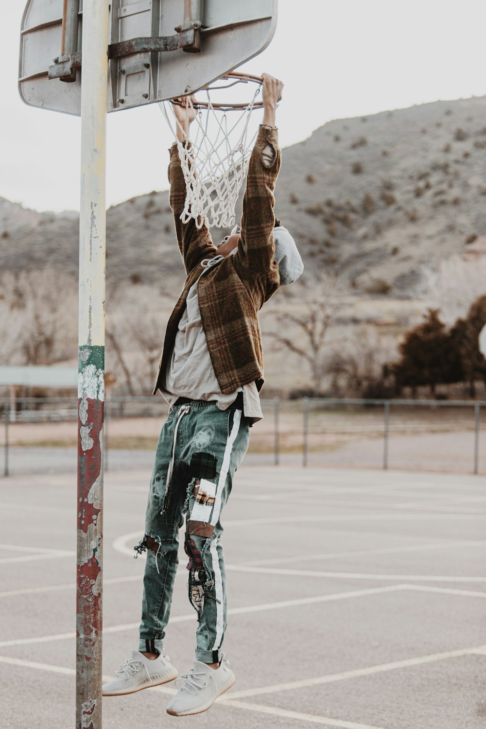 man in brown and white plaid dress shirt playing basketball during daytime