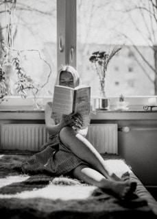 A person reading a book in a calm study space with natural light.