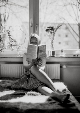 A patient reading a medical book in a bright room.