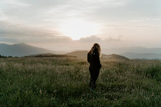 woman in black jacket standing on green grass field during daytime
