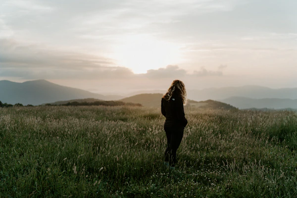 woman in black jacket standing on green grass field during daytime