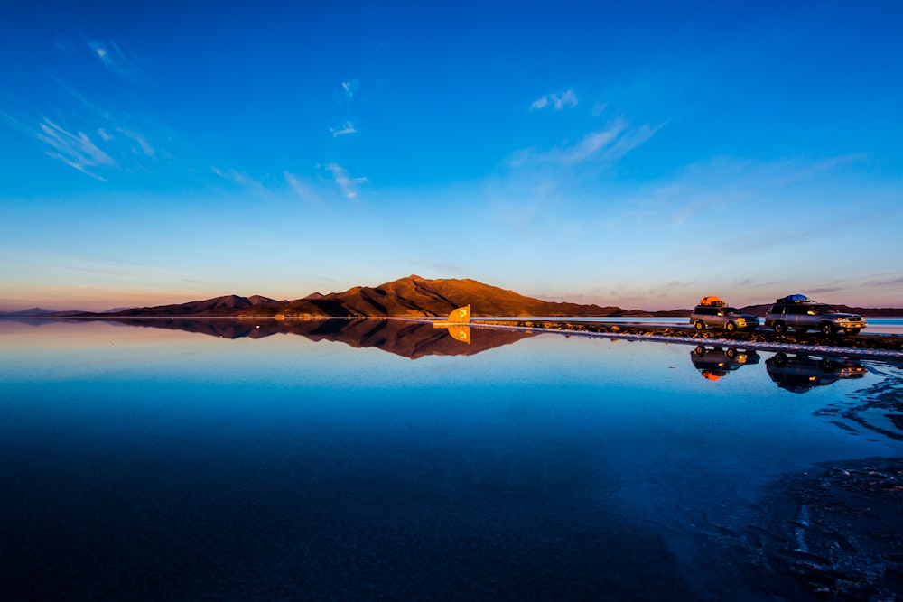 brown mountain near body of water under blue sky during daytime