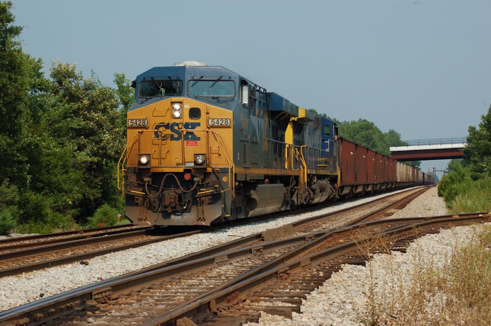 yellow and black train on rail tracks during daytime