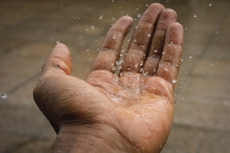 Close-up of hands holding water droplets symbolizing water preservation and sustainability.