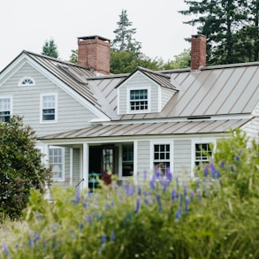 white and gray wooden house surrounded by green plants during daytime